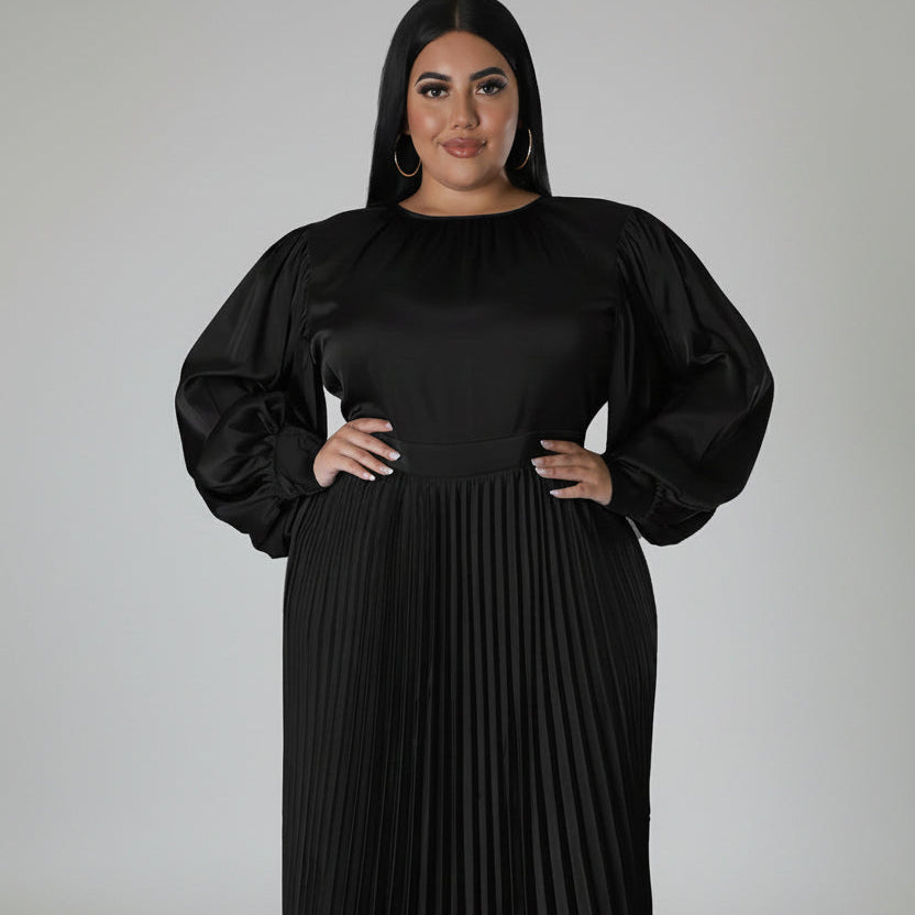 Woman wearing a black pleated dress with puff sleeves on a white background