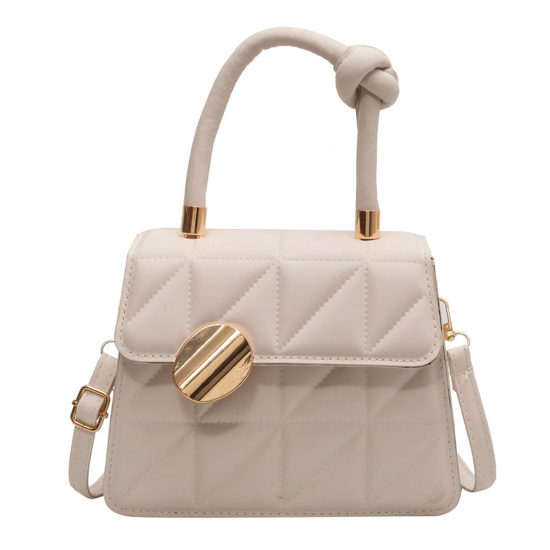 Beige handbag with gold accents on a white background