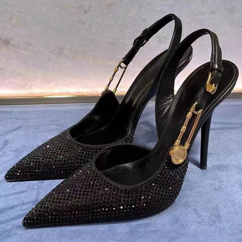 Black studded high-heeled shoes with gold accents on a light blue surface.