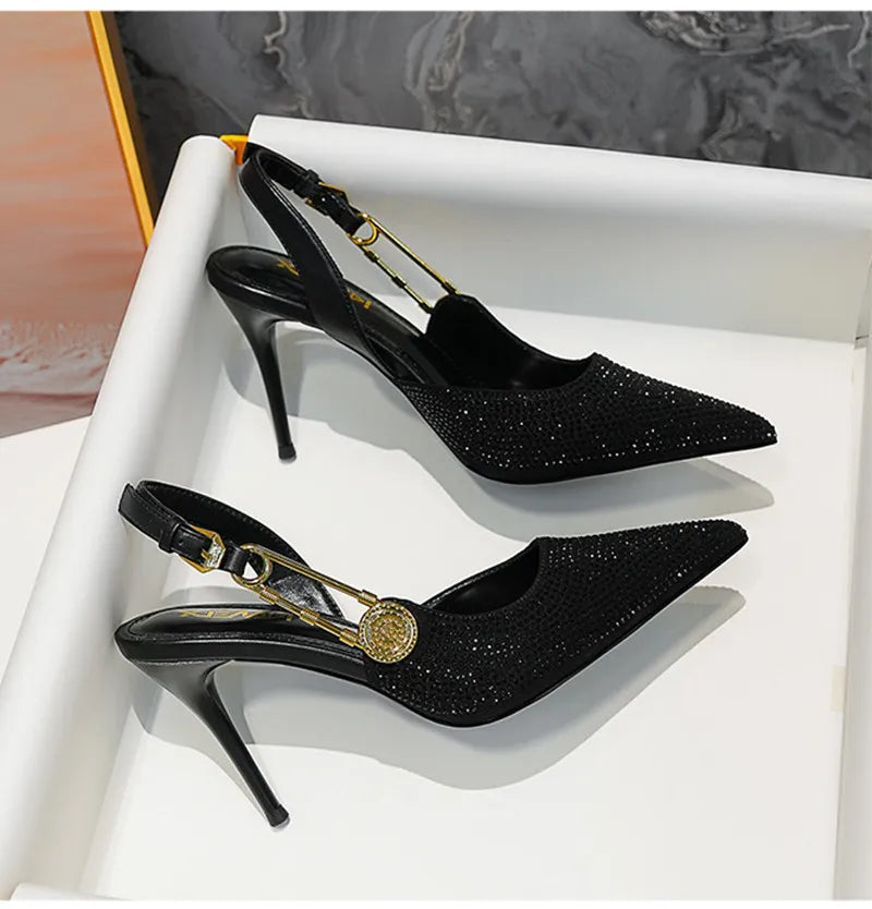 Black high-heeled shoes with gold accents on a white surface