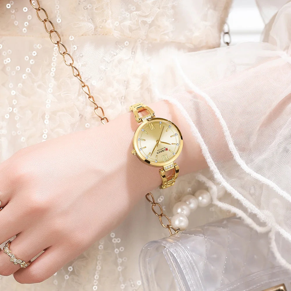 Gold wristwatch on a hand with a white background