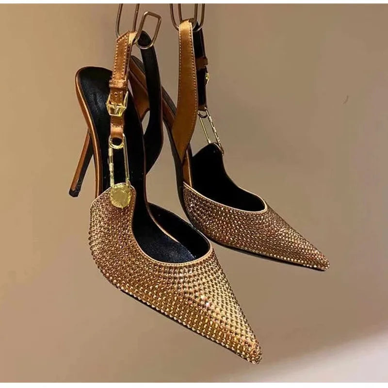 Pair of gold studded high-heeled shoes on a beige background