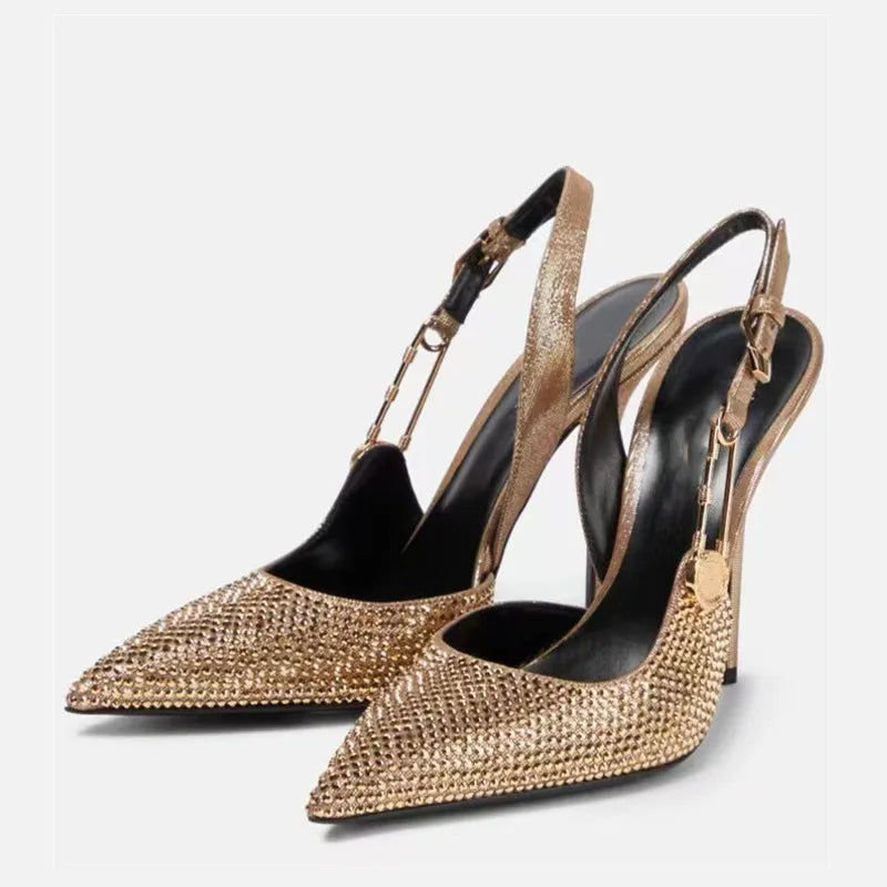 Gold studded high-heeled shoes on a light gray background
