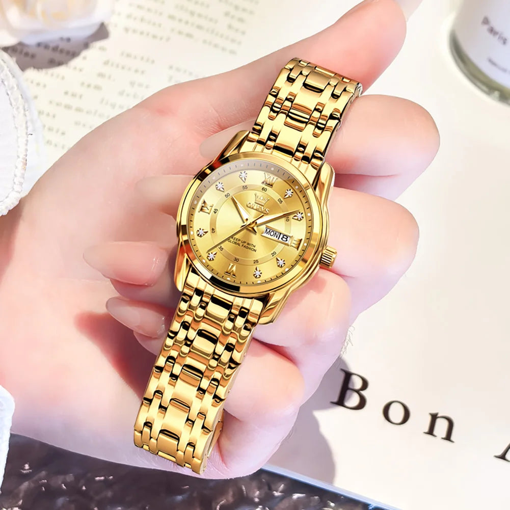 Gold wristwatch held in a hand with a blurred background