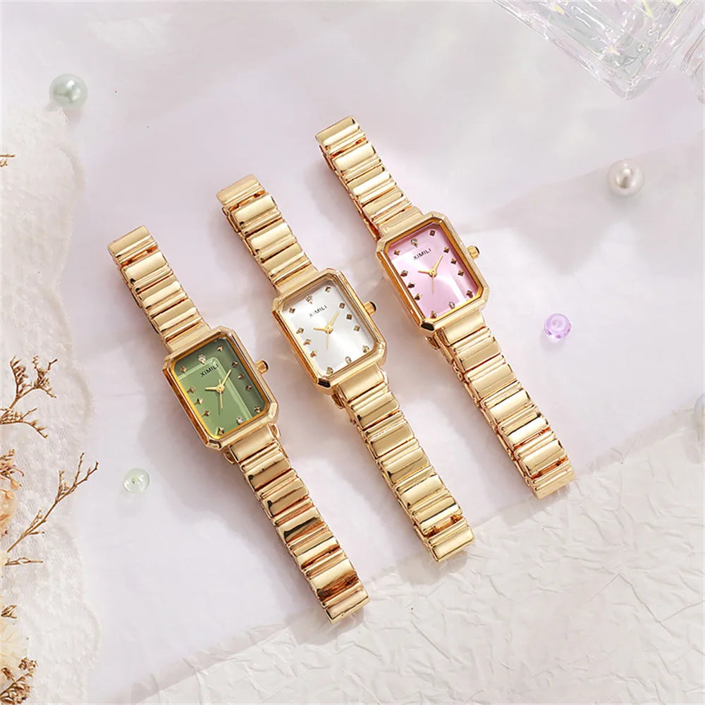 Three gold wristwatches with different colored faces on a light background