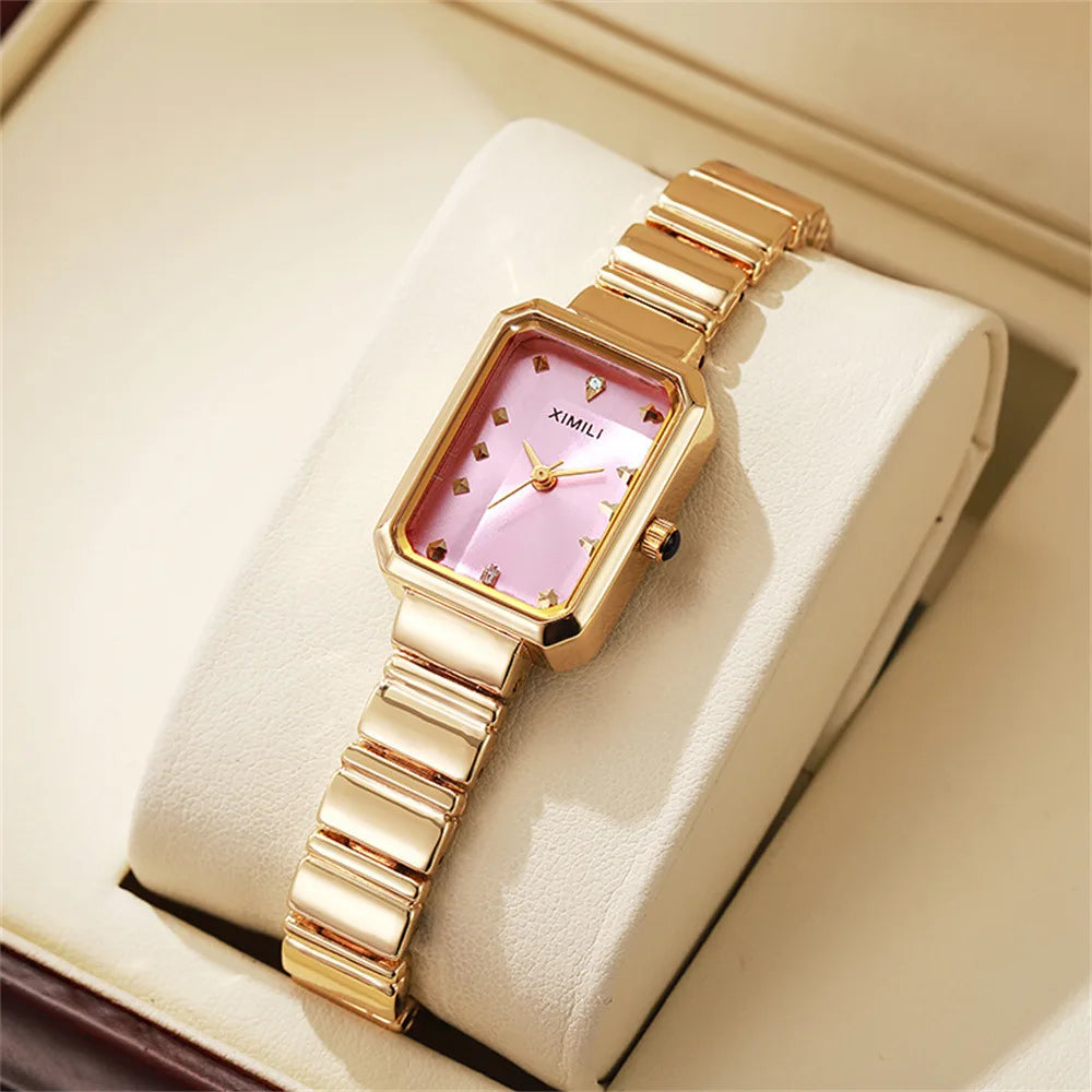Gold wristwatch with a pink face on a beige cushion in a box