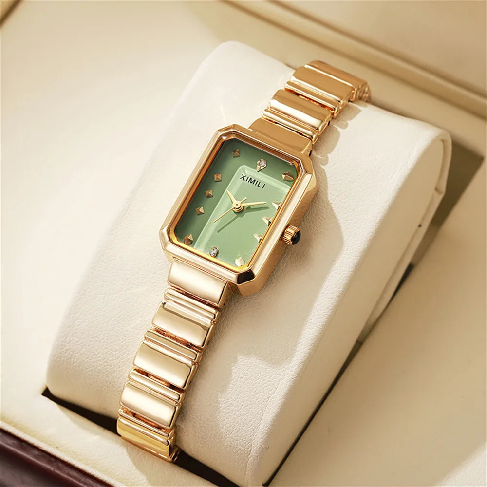 Gold wristwatch with a green face on a white cushion